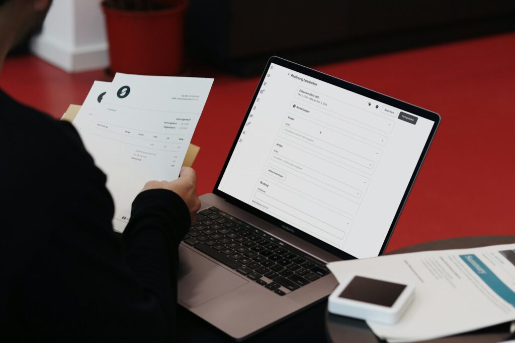 Person am Schreibtisch mit Laptop und Unterlagen bei der Einführung der E-Rechnung