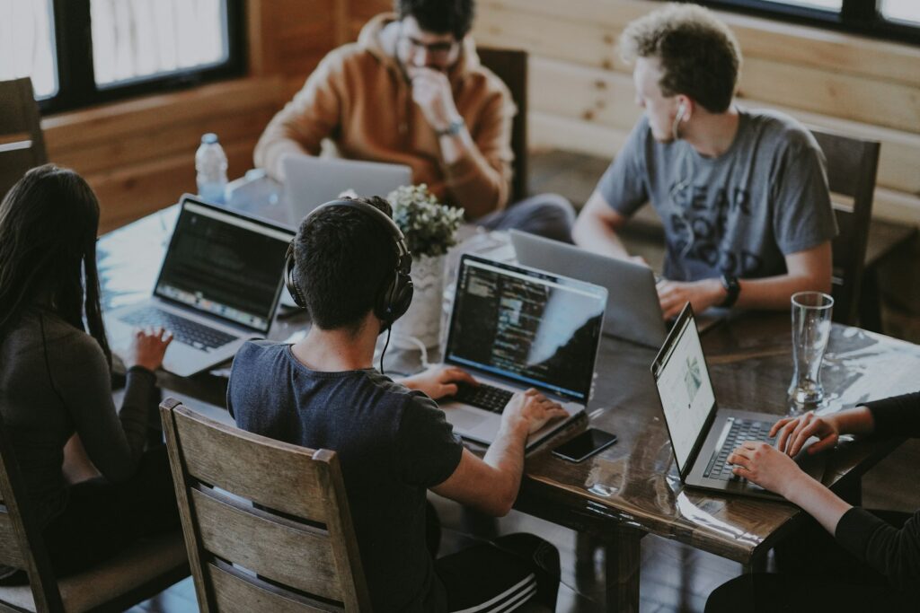 Team sitzt gemeinsam am Laptop und tauscht Ideen aus – Führung Zuhören im Teammeeting