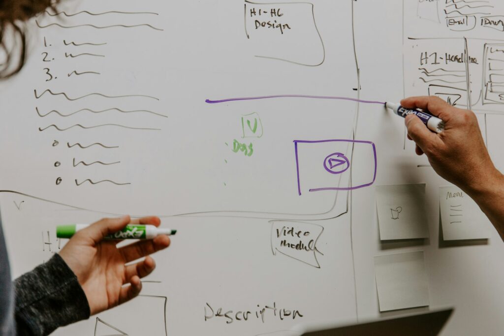 Zwei Personen skizzieren gemeinsam auf einem Whiteboard