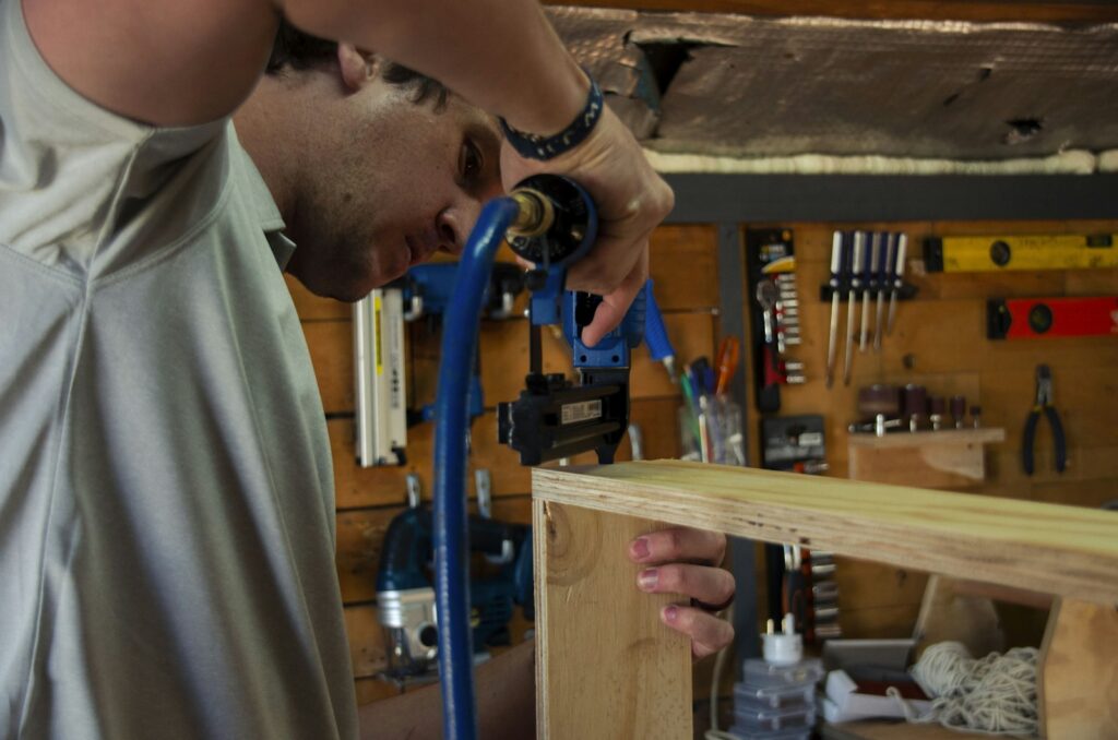 Nachfolge Familienunternehmen: Handwerker bearbeitet in seiner Werkstatt ein Werkstück aus Holz