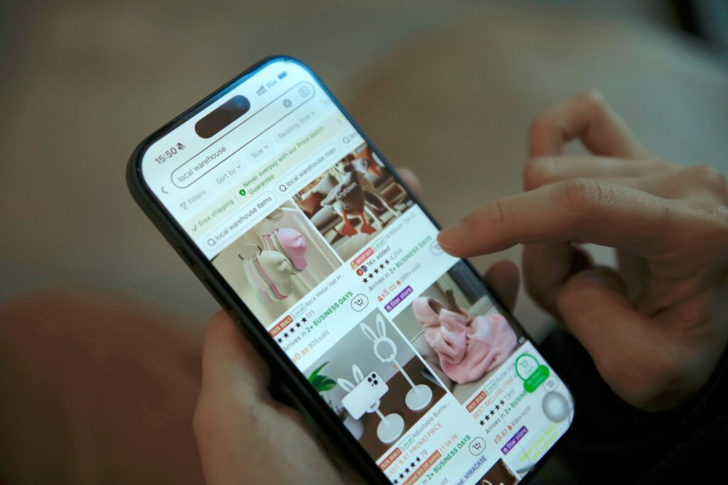 Person scrollt auf dem Smartphone durch einen Shop – Onlinehandel Einkaufsverhalten mobil